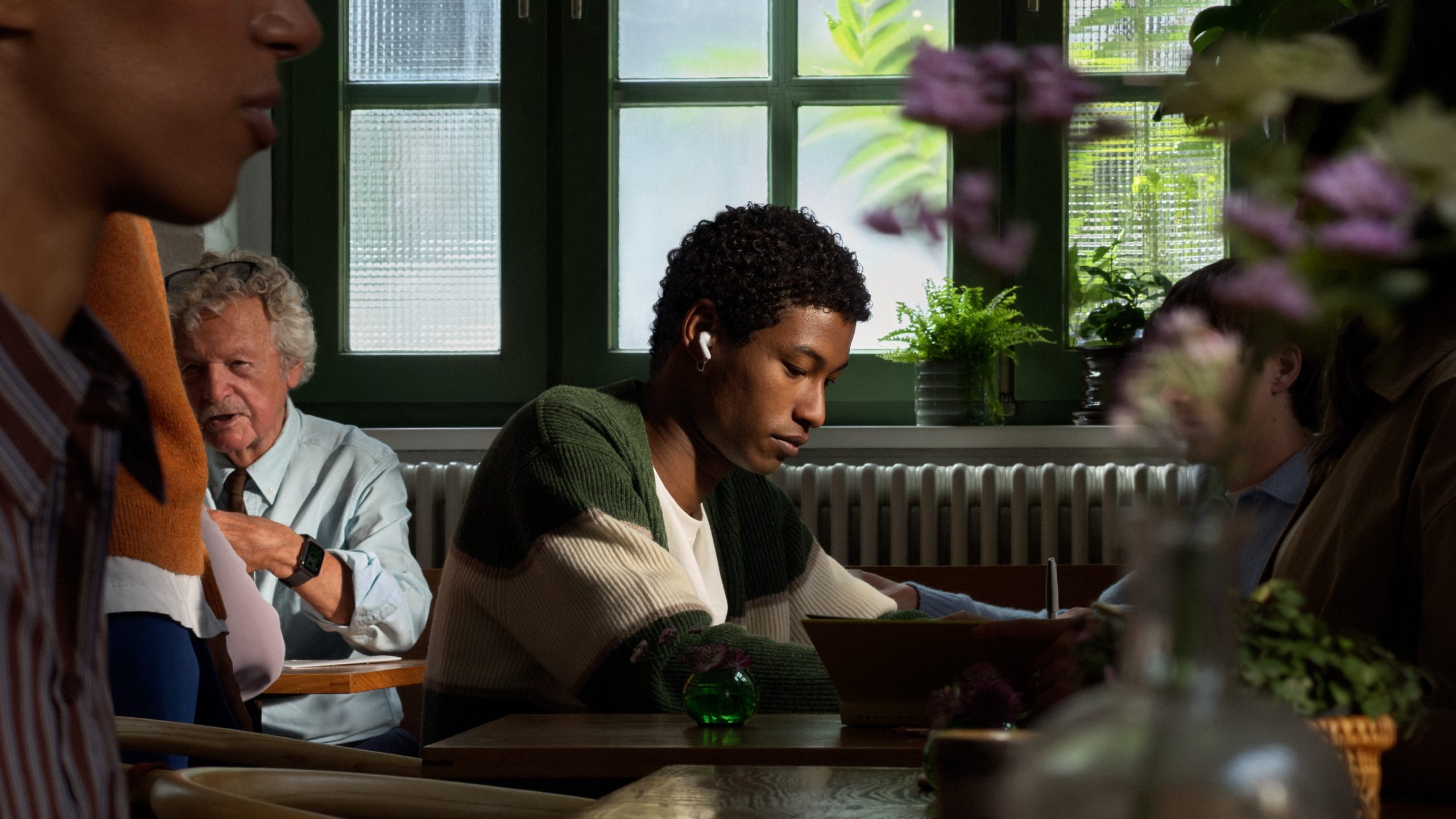 En person bruger AirPods 5 på en café
