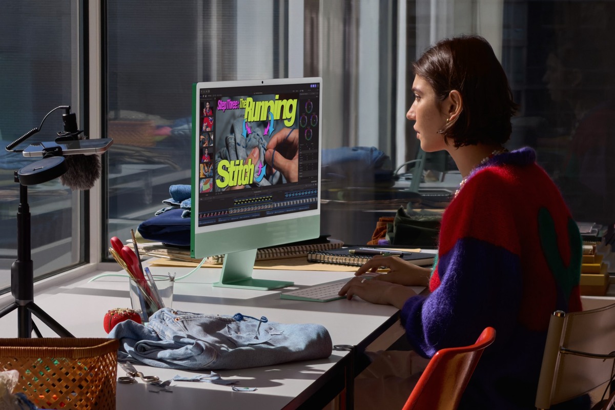 En bruger redigerer video på en grøn iMac med M6 ved en arbejdsplads med et syprojekt.